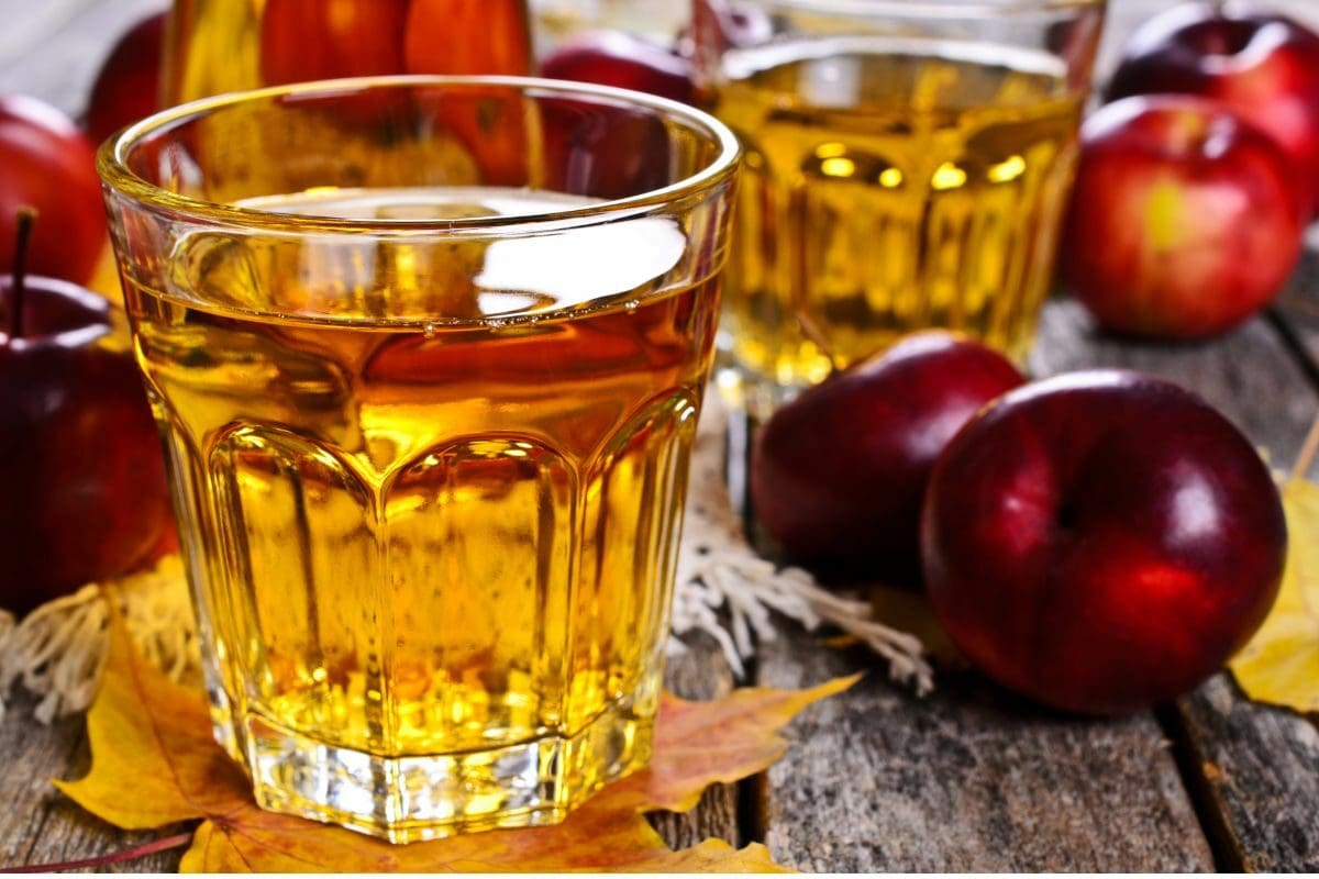 Apple Juice Filled in a Glass and Surrounded with Fresh Red Apples