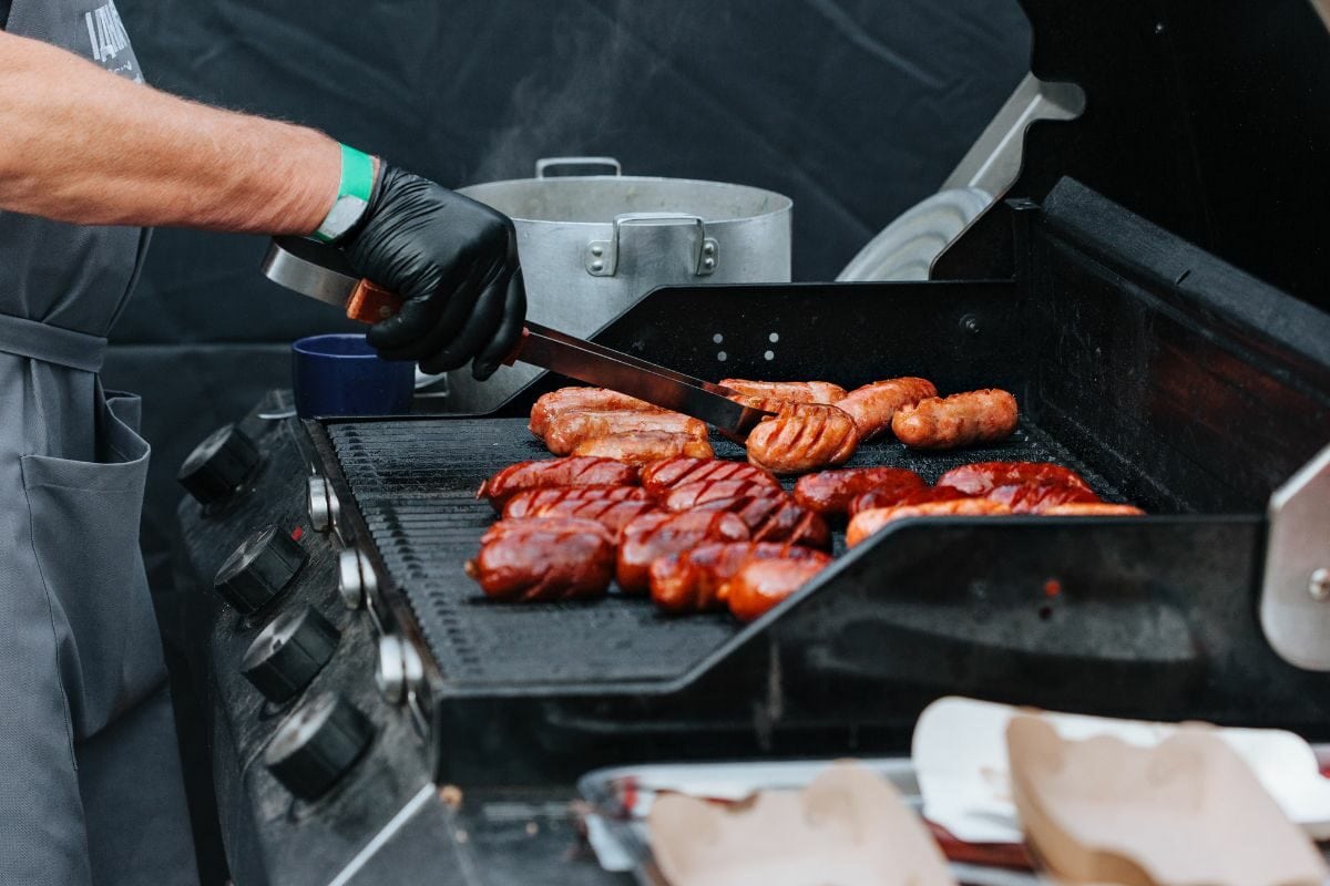 Person Grilling Sausages