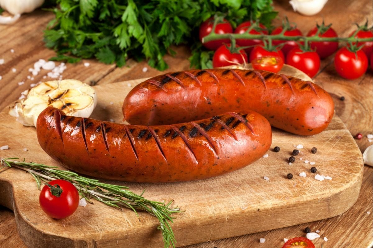 Grilled Sausages and Tomatoes on the Wooden Board