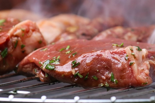 A juicy raw rump steak cooking on a barbecue