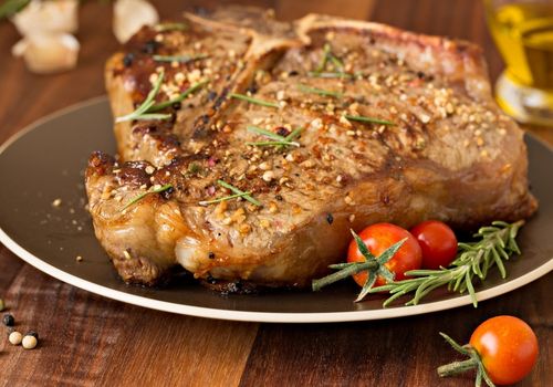 T bone steak garnished with rosemary and cherry tomatoes