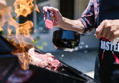 Man Rubbing BBQ Sauce on the Grilling Meat