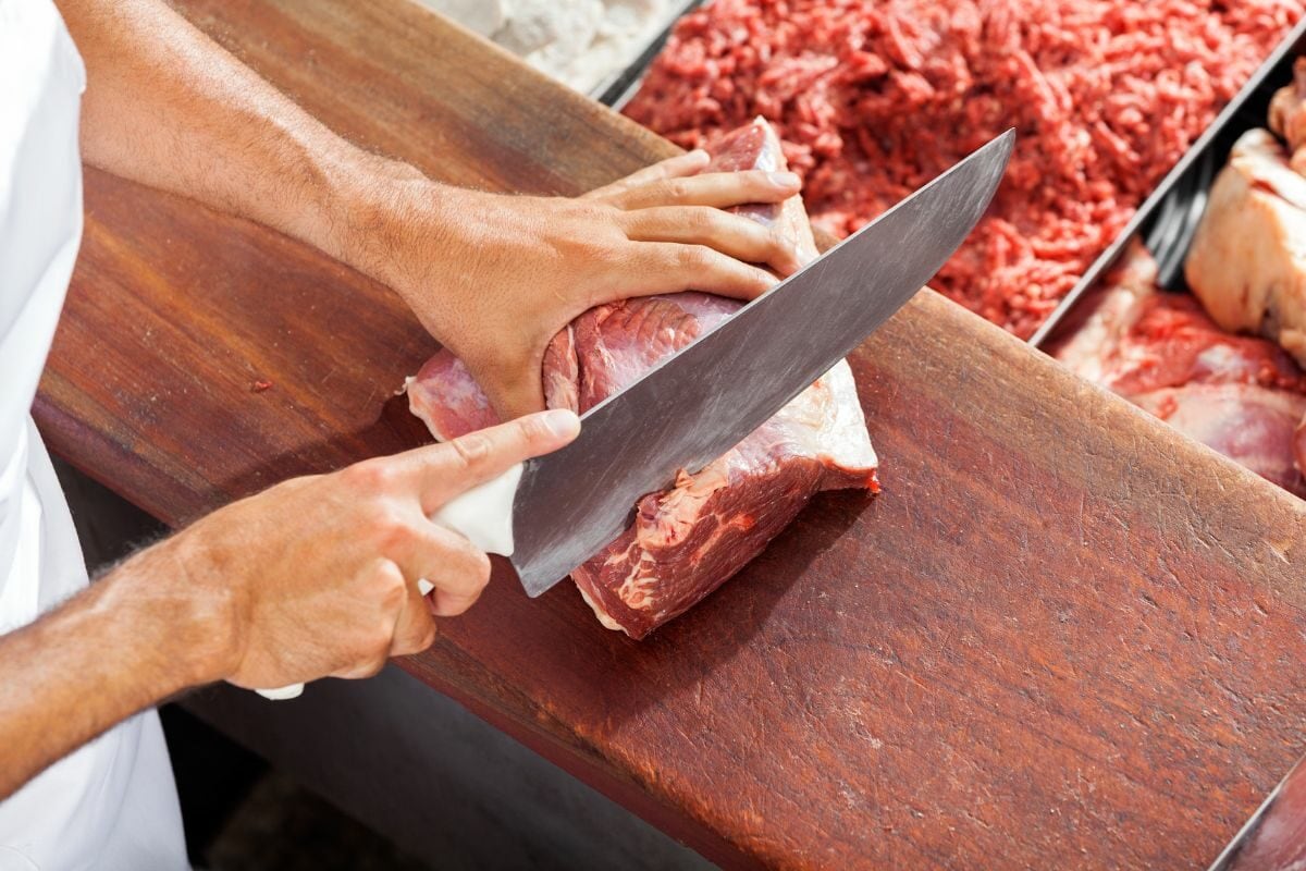 Butcher Cutting Meat At Counter