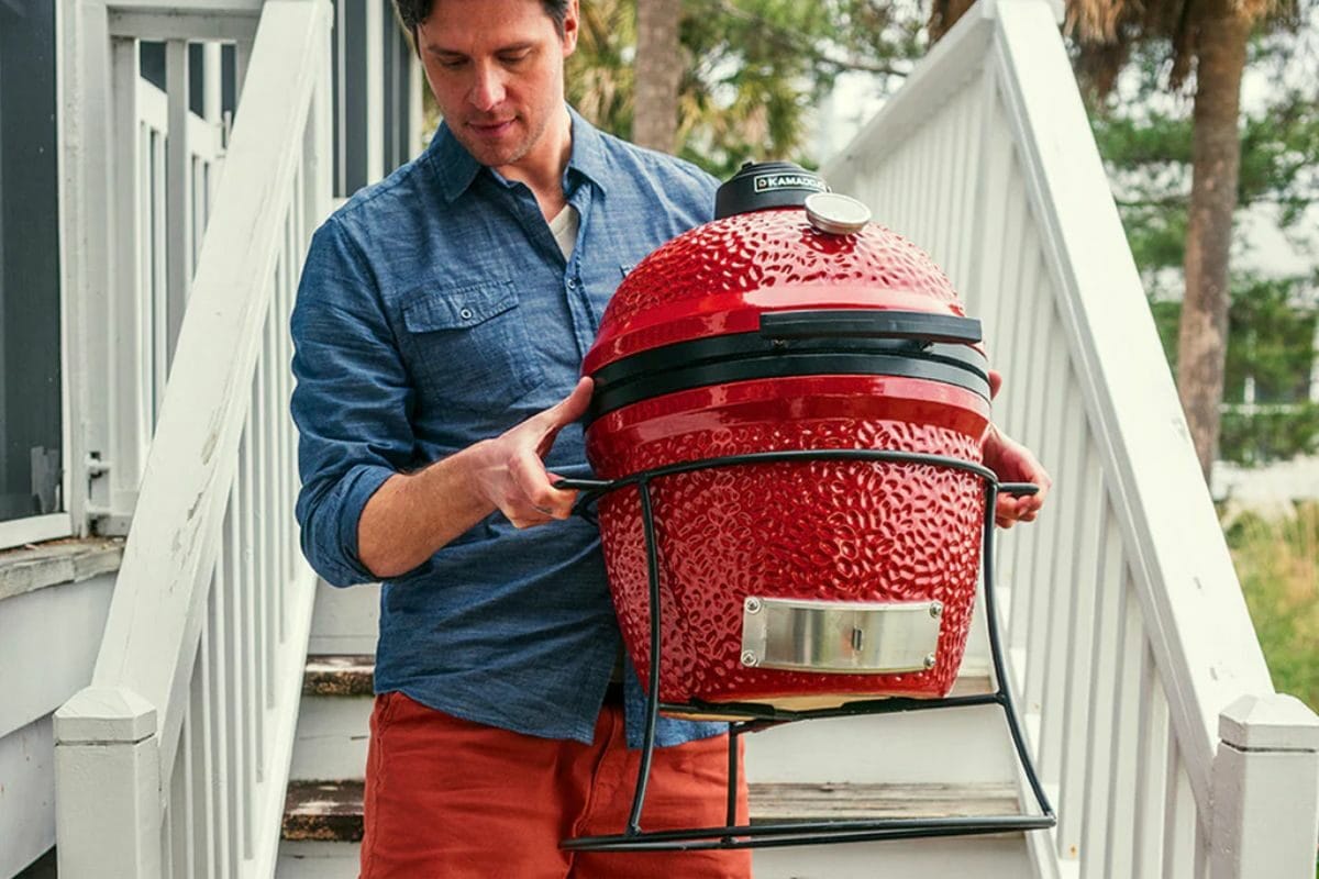 Person Carrying Kamado Joe JR Grill with Cast Iron Stand