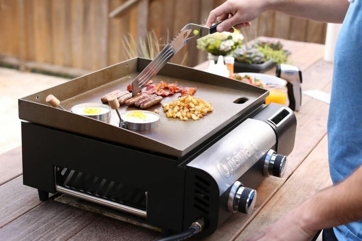 Person Grilling Food on Cuisinart CGG-501 Gourmet Gas Griddle