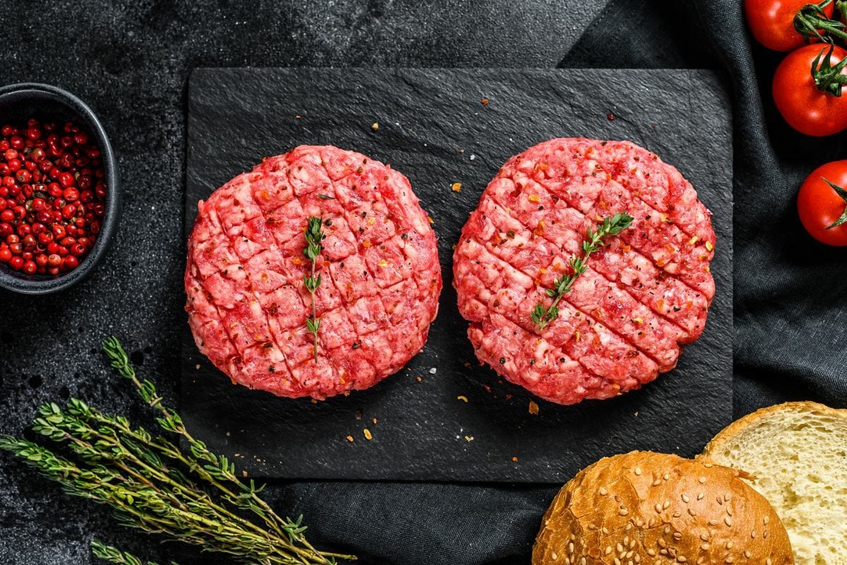 Raw Burger Patties with Burger Buns, Tomatoes, and Spices