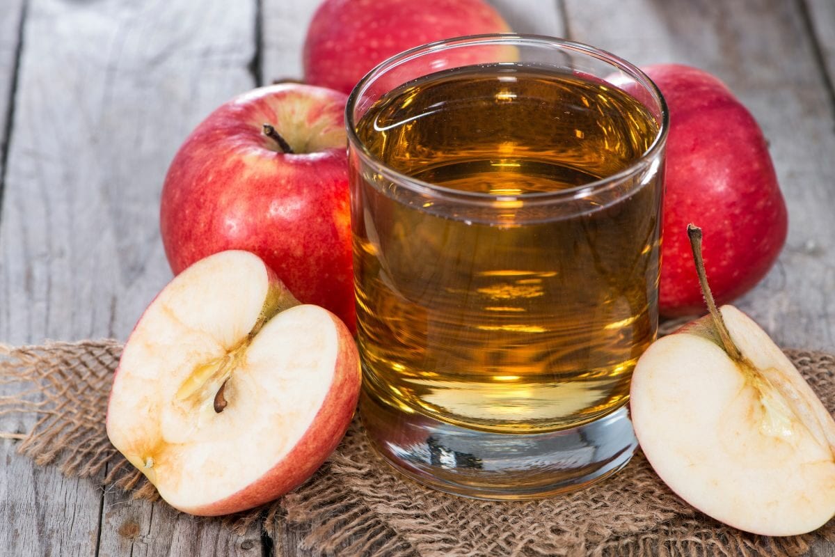 A Small Glass of Apple Juice with Some Apples