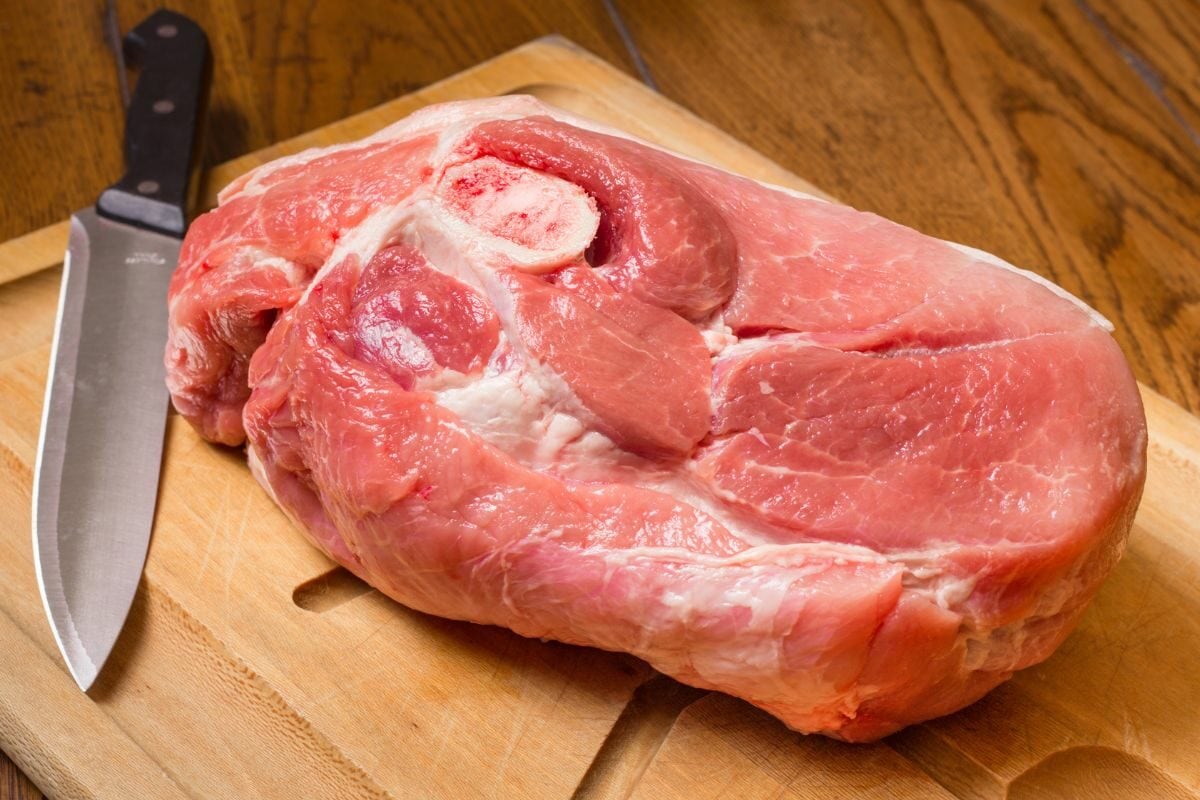 Raw Pork Shoulder Placed on the Chopping Board along with a Knife