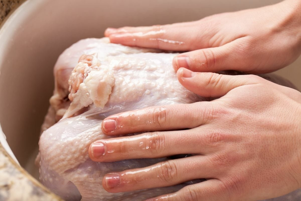 Hands Rubbing Olive Oil Over Raw Turkey